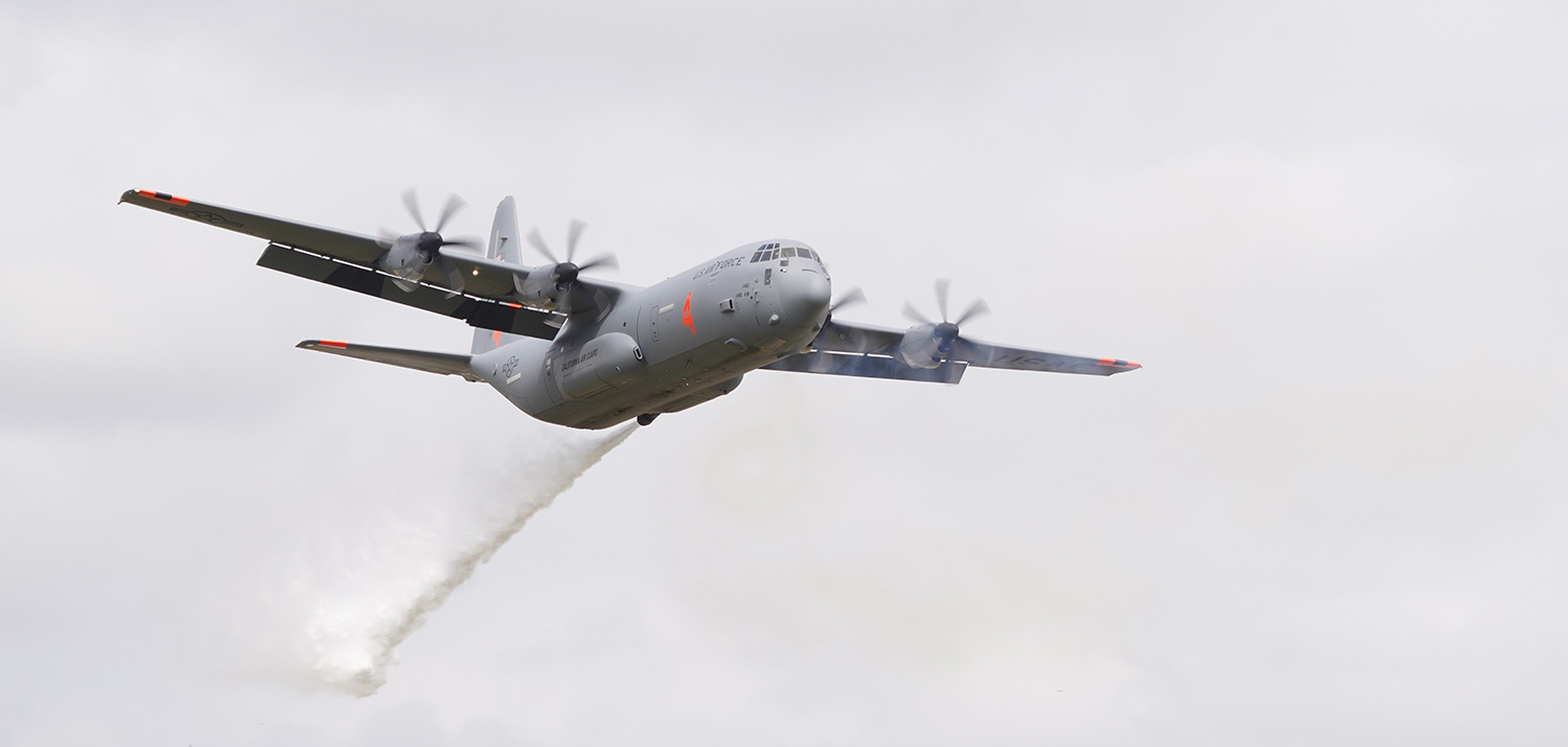A large plane with four propellers flies overhead